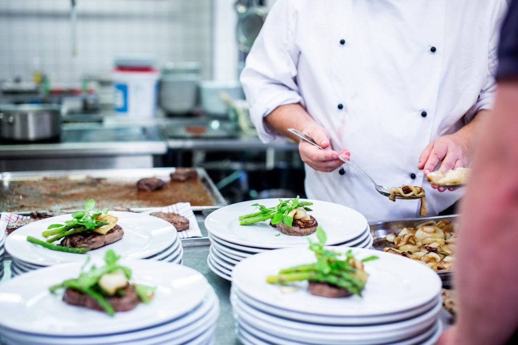 pexels photo 2977514 A chef prepares gourmet dishes in a professional kitchen setting, showcasing fine dining elegance.